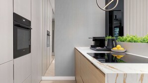 Ett modernt kök med inbyggda vitvaror, en bänkskiva i marmor och en kaffebryggare.
