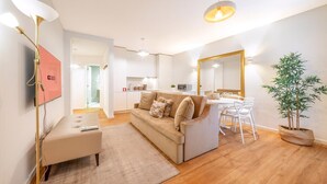 Un salon moderne comprenant un canapé, une table basse, un coin repas avec des chaises, un grand miroir et une plante en pot.