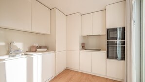 Une cuisine moderne avec des meubles blancs, un évier en acier inoxydable et un four encastré.