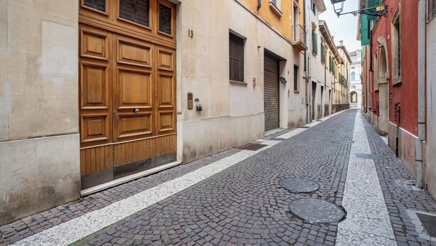 A narrow cobblestone street flanked by historic buildings with large wooden doors and shutters. - Elegant Apartment 300 Meters from the Arena with balcony (Verona)