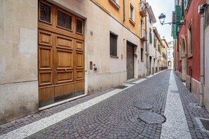 A narrow cobblestone street flanked by historic buildings with large wooden doors and shutters. - Elegant Apartment 300 Meters from the Arena with balcony (Verona)