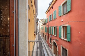 Une rue étroite, bordée de bâtiments des deux côtés, avec des balcons et des volets traditionnels.