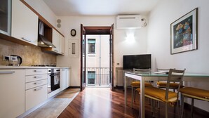 A modern kitchen with white cabinets, a gas stove, and a dining area with a glass table and metal chairs. - Elegant Apartment 300 Meters from the Arena with balcony (Verona)