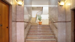 A marble staircase with a wooden door on the left, a potted plant at the top, and glass railings. - Elegant Apartment 300 Meters from the Arena with balcony (Verona)
