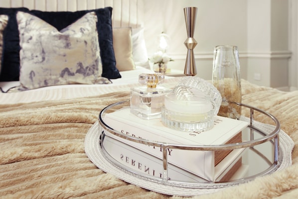 A bed with a fluffy blanket, a tray with perfume bottles, and a book titled "SENTIMENTY". - Mayfair Opulence Residence (London)