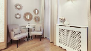 Ein Zimmer mit einem karierten Sessel, einem runden Tisch und einer dekorativen Konsole mit Netzmuster.