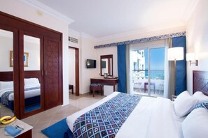 Een hotelkamer met een groot bed, een bureau met stoel, een televisie en een balkon met uitzicht.