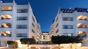 Een meerlaags hotel met een symmetrische gevel, centrale ingang en balkons op elke verdieping.