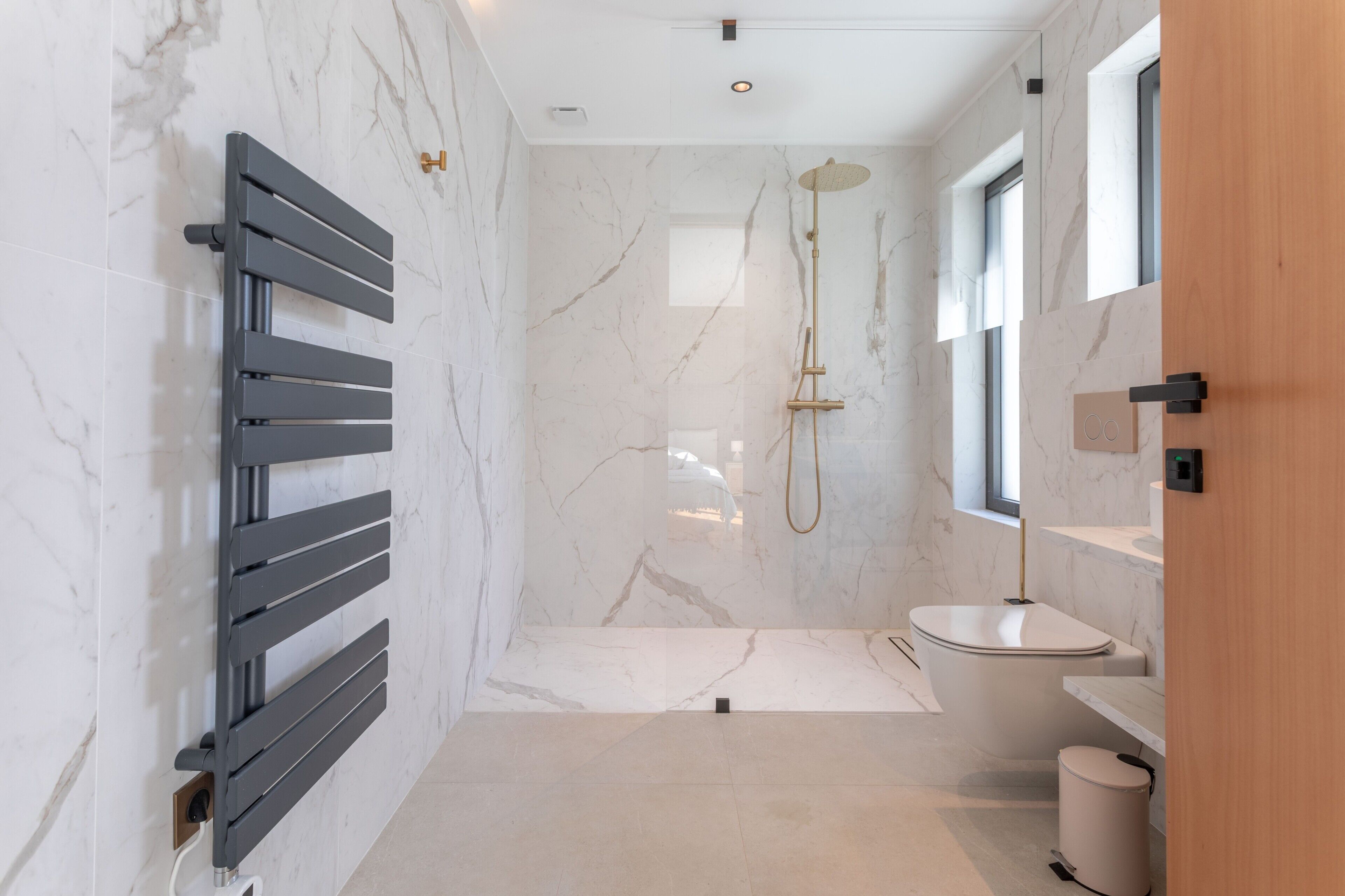 A modern bathroom with a shower, toilet, and a towel rack.