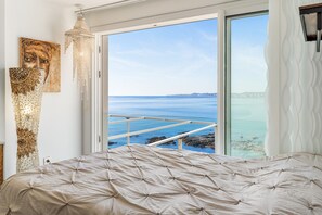 A bedroom with a bed, a large window with a view of the sea, and a chandelier. - Duplex 'Paradise Over the Sea' with Sea Views, Wi-Fi and Air Conditioning (Benalmádena)
