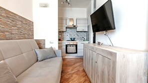 A modern kitchen with a built-in oven, a flat-screen TV mounted on the wall, and a wooden countertop. - Appartamento Blue Mare - Gorgeous Sea View (Sardegna)