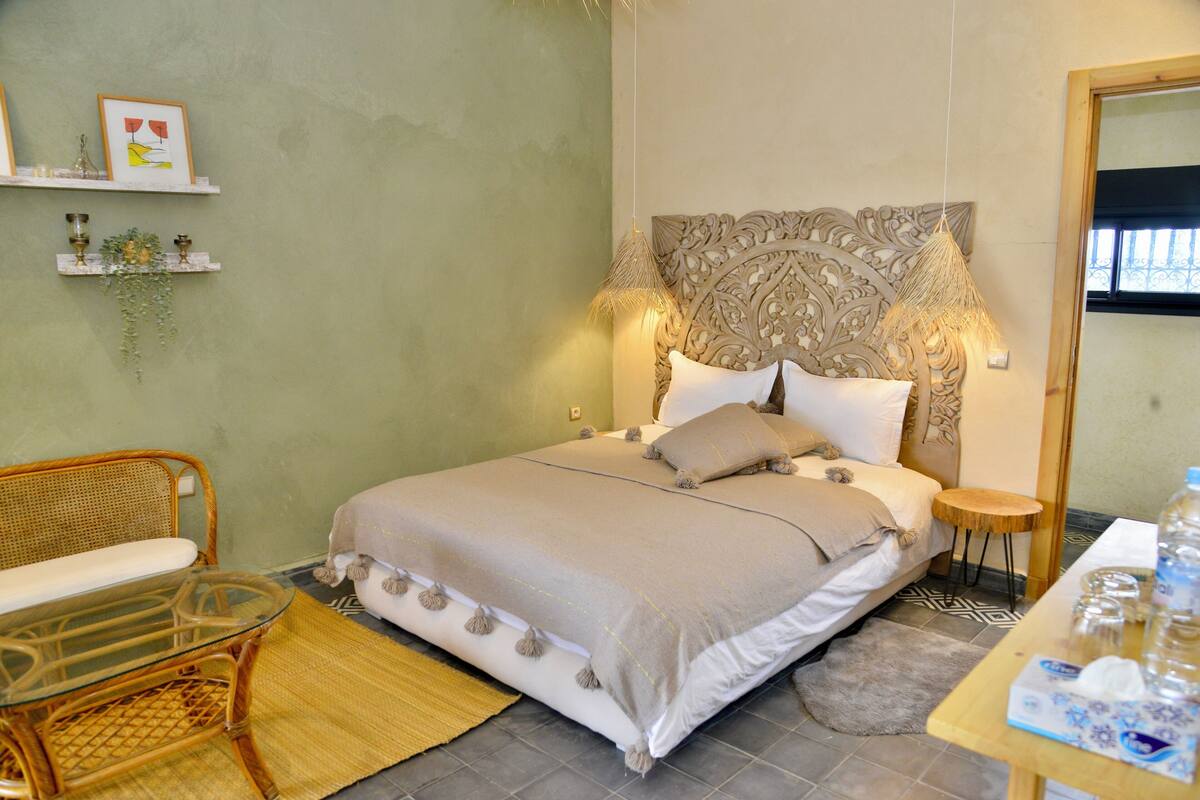 A neatly arranged bedroom with a bed, bedside tables, a chair, and a small table with items on it.