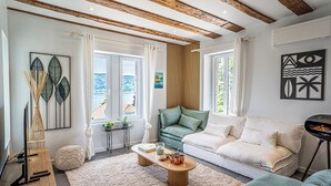 Ett modernt vardagsrum med ett träpanelat tak, en grön soffa, en vit soffa och ett soffbord med dekorativa föremål.