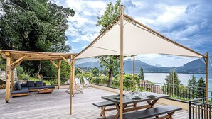 Ett trädäck med ett bord och bänkar, en soffa och en pergola med ett tak.