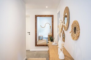 Ein Flur mit einer Holztür, die zu einem Raum führt, ein Holztische mit einer Vase und dekorativen Spiegeln.