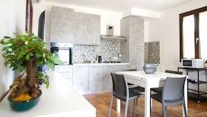 A modern kitchen with grey cabinets, a white countertop, and a dining area with two chairs.