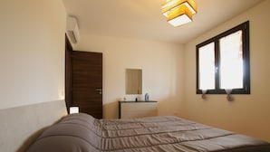 A bedroom with a bed, a dresser, a mirror, and a window with curtains.