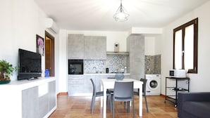 A compact kitchen with a dining area, a washing machine, and a flat-screen TV.
