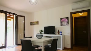 A dining area with a table and chairs, a flat-screen TV, a potted plant, and artwork on the walls.