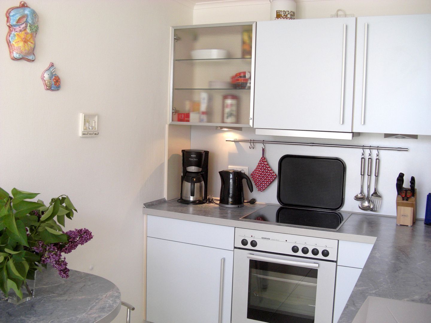 Una cocina compacta con estufa, horno, cafetera y microondas.