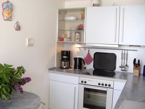 Une cuisine compacte équipée d’une cuisinière, d’un four, d’une machine à café et d’un four à micro-ondes.