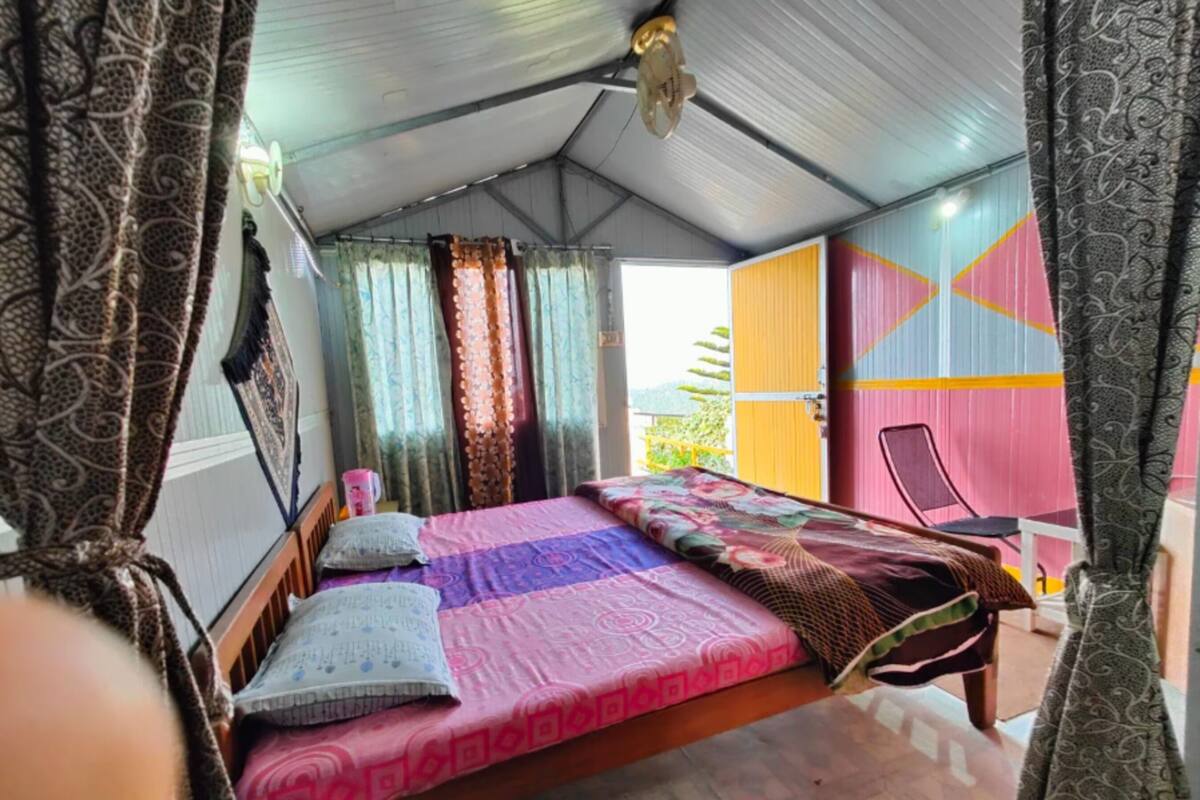 A bedroom with a bed, curtains, and a view of the outside.