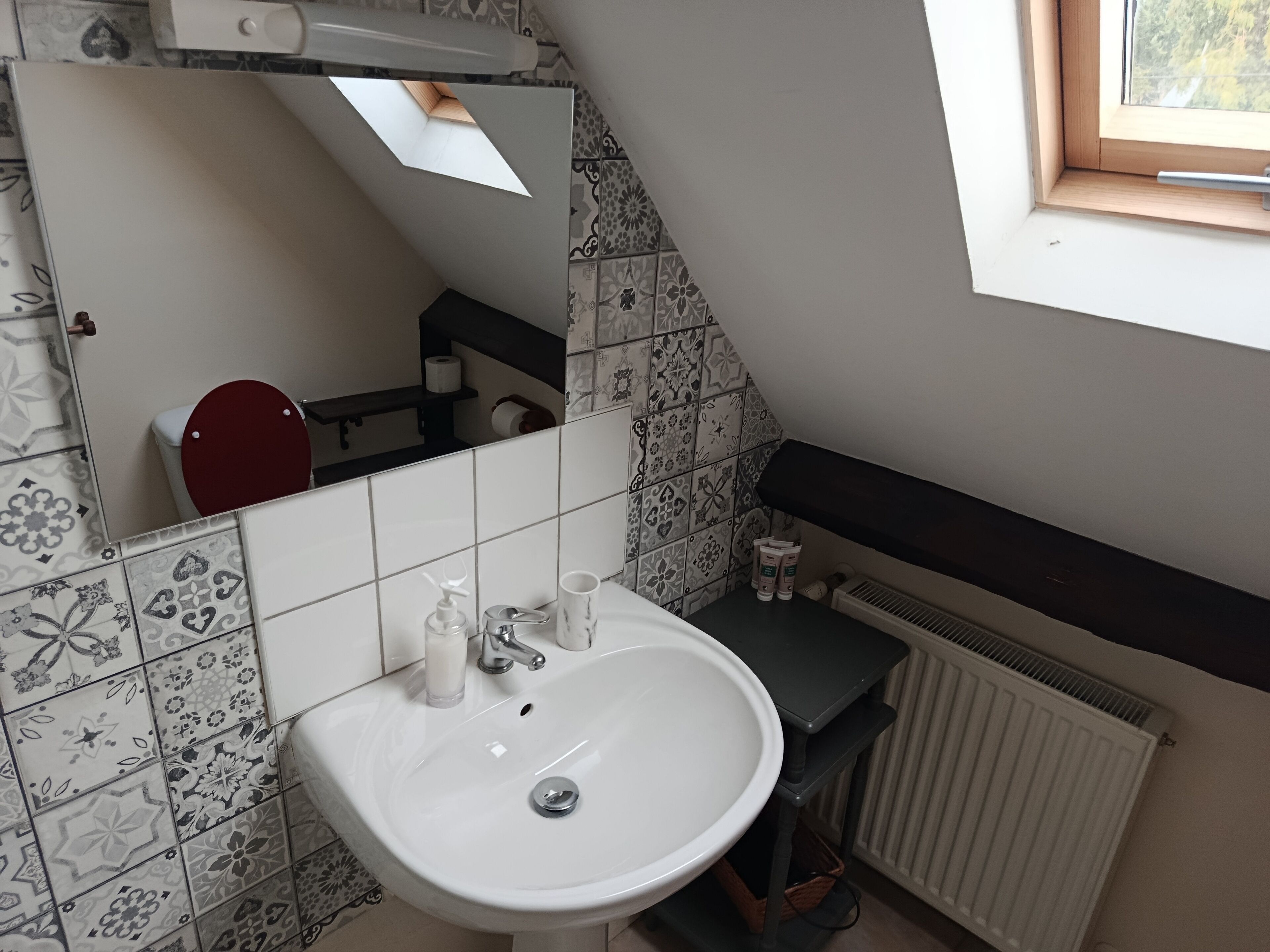 Un baño con un lavamanos blanco, un inodoro rojo y un espejo.