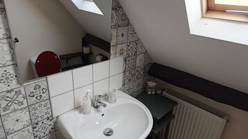 Un baño con un lavamanos blanco, un inodoro rojo y un espejo.