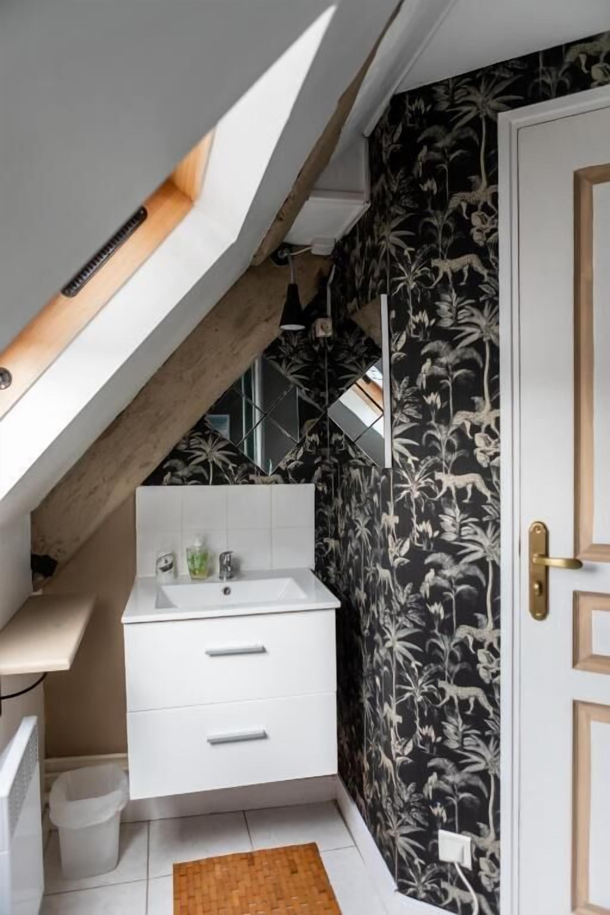 A compact bathroom with a white vanity, a small sink, and a shower area.