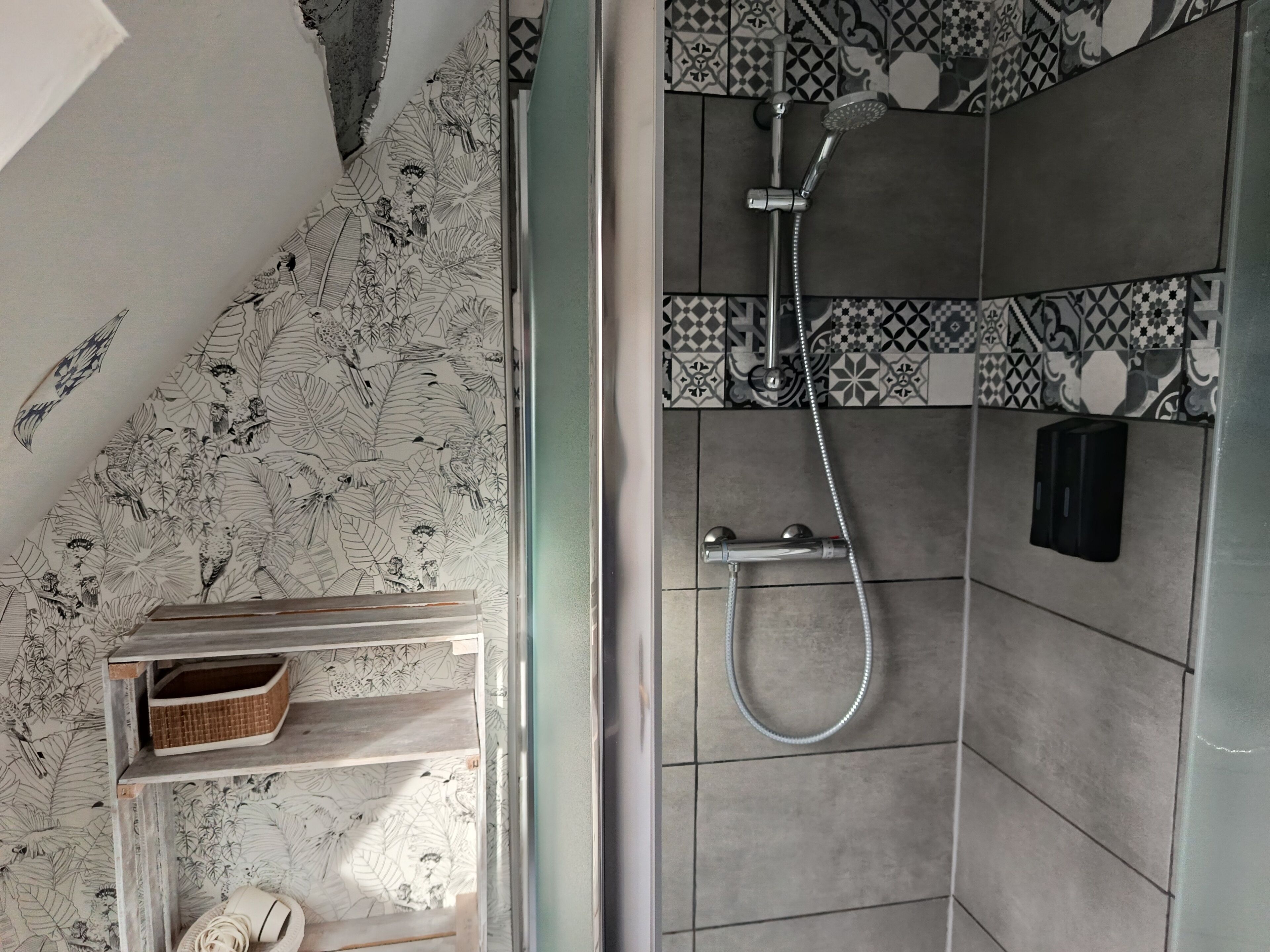 A bathroom with a shower, tiled walls, a shelf with a basket, and a towel.