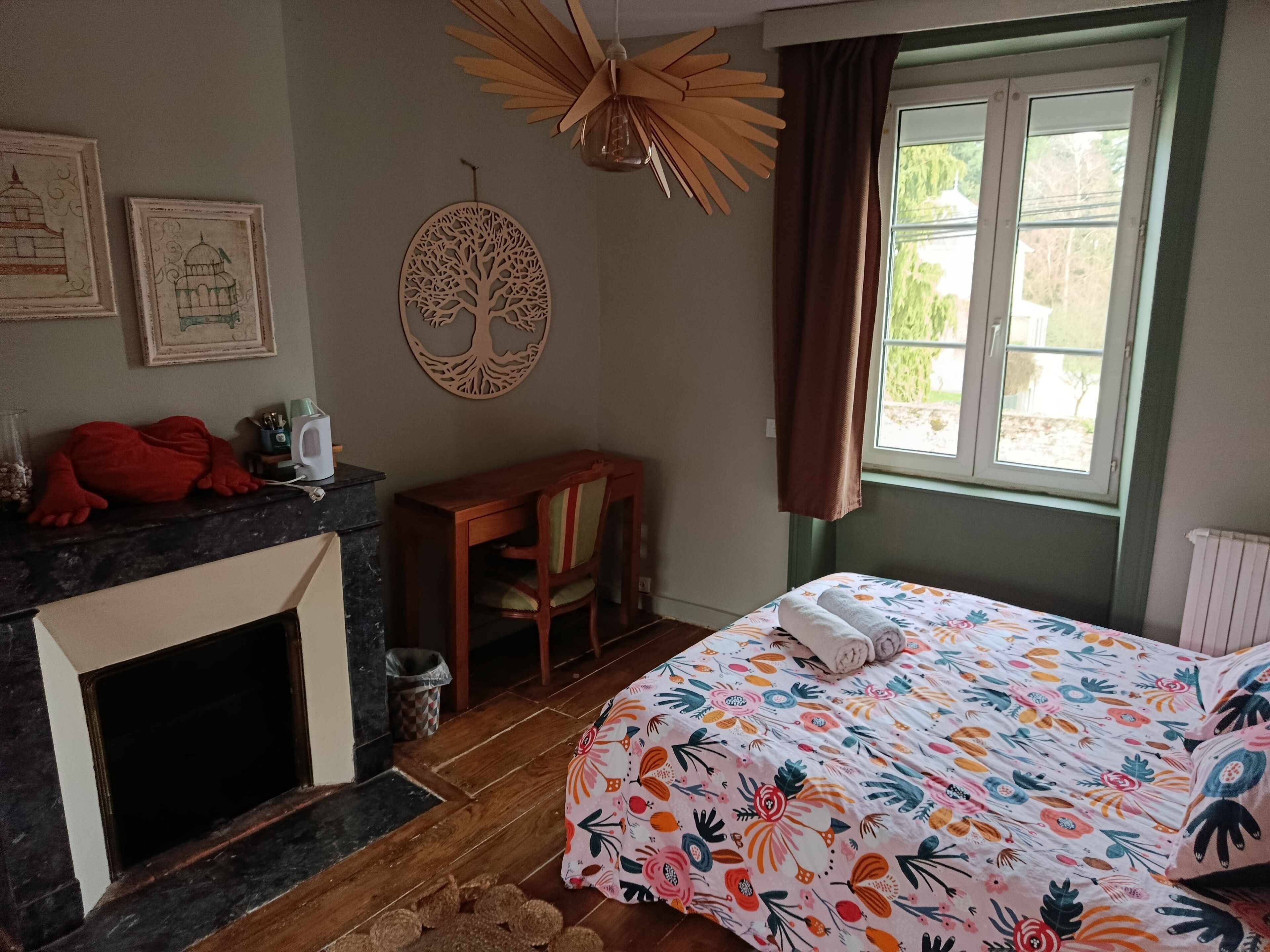 Un dormitorio con cama, una silla, chimenea y ventana.