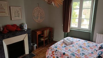 Un dormitorio con cama, una silla, chimenea y ventana.
