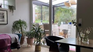 A modern room with a large window, a dining table, chairs, and a bed with a purple bedspread. - Atipyk'Ododo (Saint-James)