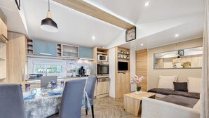 Et moderne køkken med indbyggede apparater, et spiseområde med bord og stole, og en hyggelig opholdsstue med sofa og fjernsyn.