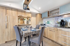Een moderne keuken met houten kastjes, een eettafel gedekt voor vier personen en een koffiezetapparaat op het aanrecht.