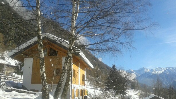 A snow-covered mountain house with a wooden exterior and a stone foundation. - CUCOL HUT (Trentino-Alto Adige)