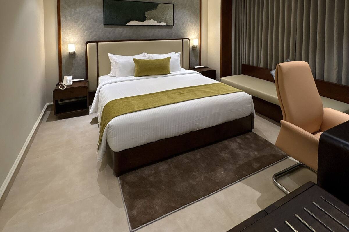Una habitación de hotel moderna con una cama grande, mesitas de noche, un escritorio y una silla.
