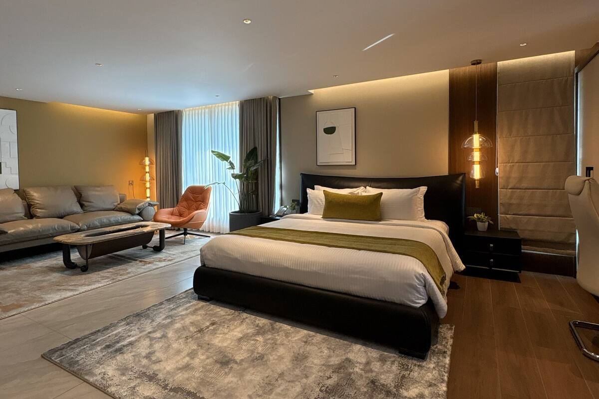 Un dormitorio moderno con una cama grande, un sofá, una silla y una mesita.
