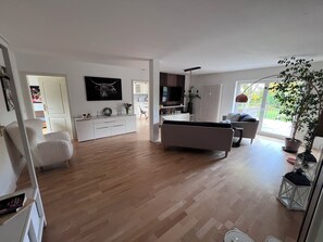 Uma sala de estar moderna com sofá, televisão e um espaço de jantar com mesa e cadeiras.