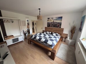 A bedroom with a wooden bed, a cityscape painting, a wardrobe, and a mirror. - Baltic Sea Lounge beautiful, bright large apartment 100sqm in Kühlungsborn (Kühlungsborn)