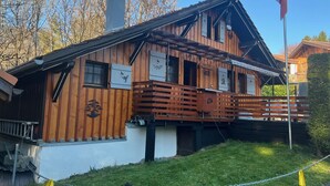 Une cabane en bois avec un balcon, une cheminée et un drapeau.
