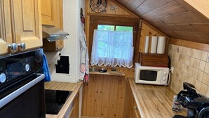 Une cuisine compacte avec des meubles en bois, une cuisinière, un four à micro-ondes et une machine à café.