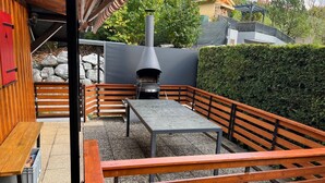 Une terrasse extérieure avec une table et des bancs en pierre, une clôture en bois et un mur en pierre.