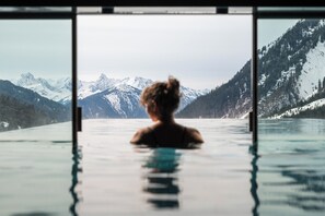 A person in a swimming pool with a view of snow-capped mountains. - Wohlfühlhotel Hubertushof (Klosterle am Arlberg)