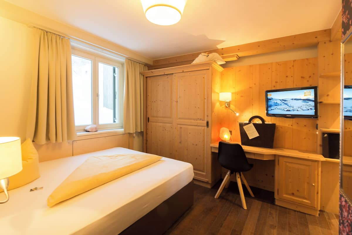 Ein Hotelzimmer mit Bett, Schreibtisch, Stuhl, Fernseher und Holzwandverkleidung.