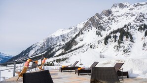 Una terrazza con poltrone relax e vista sulle montagne innevate.