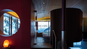 Un interno moderno con una finestra circolare, una lampada di sale e vista sulle montagne innevate.