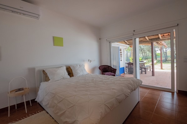 Ein Schlafzimmer mit Bett, Sessel und einer Schiebetür zum Außenbereich.