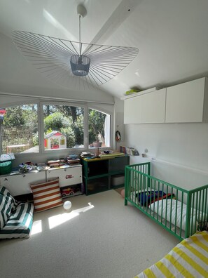 A child's room with a crib, a desk, and a window overlooking greenery. - Villa between lake and ocean, view of white beach (Soorts-Hossegor)