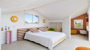 Ein Schlafzimmer mit Bett, Fenster, Bad und einem kleinen Tisch mit Spielzeug.